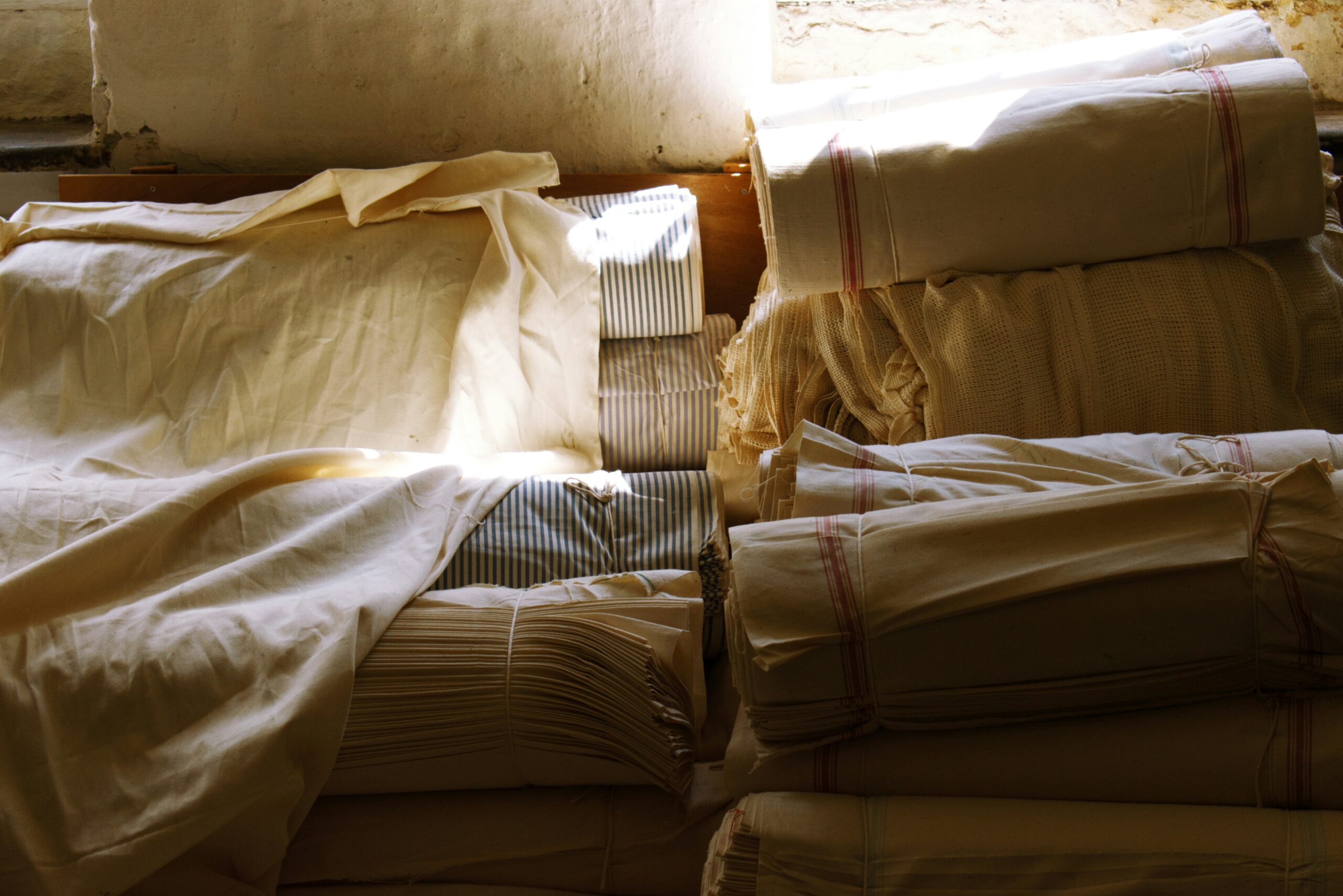 Stacked folds of natural cotton and linen cloth in warm daylight