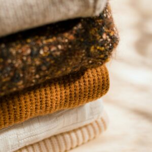 A stack of folded knitwear in warm tones
