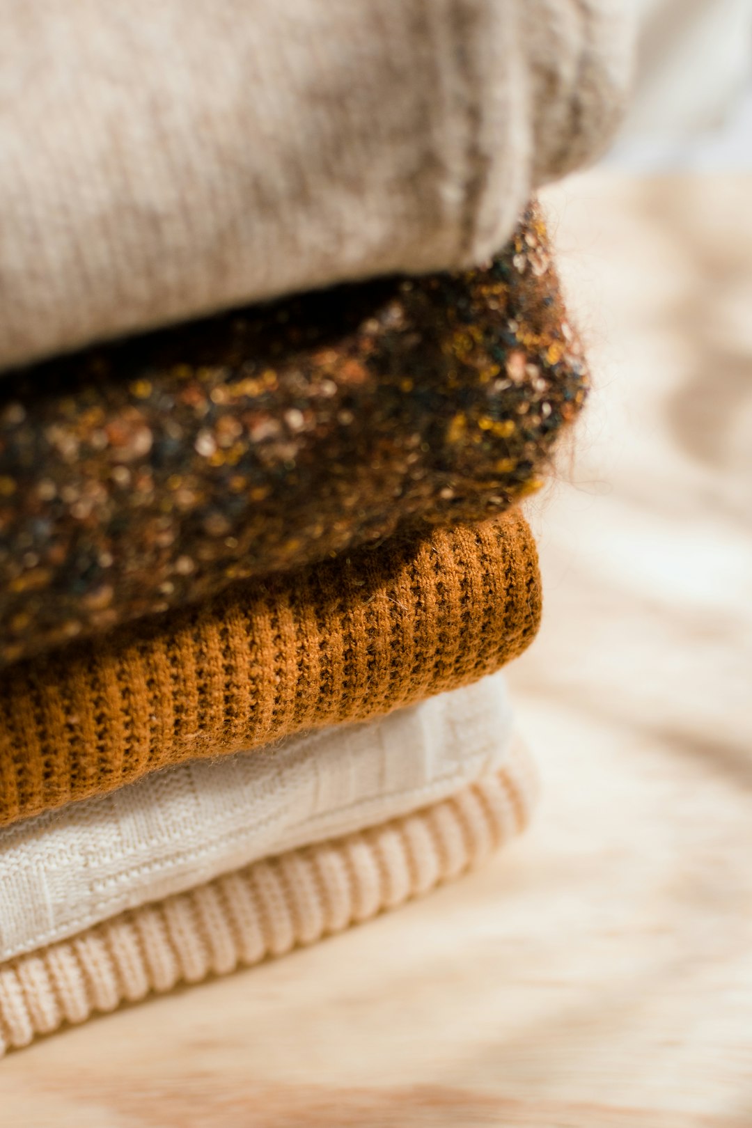 A stack of folded knitwear in warm tones
