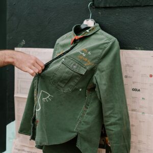 A green cotton overshirt held up by its shoulders