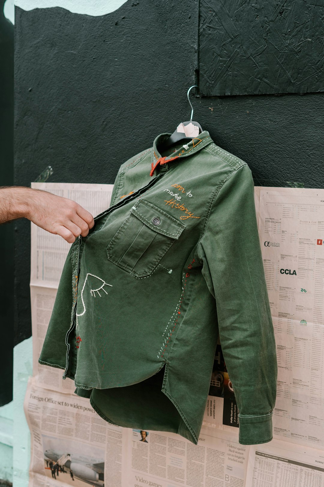 A green cotton overshirt held up by its shoulders